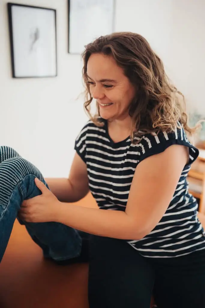 Claudia Hannemann, Trainerin für Reflexintegration und Gründerin der Awesome Academy, bei der Anwendung einer Übung zur Reflexhemmung mit einem Kind auf der Behandlungsliege.