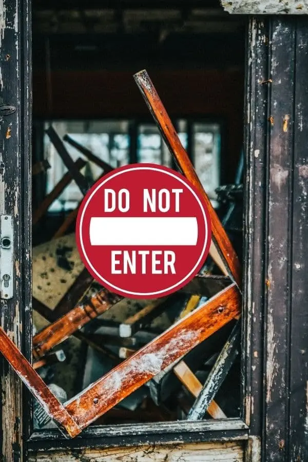 Zerstörte Tür mit Holztrümmern, durch die ein ‚Do Not Enter‘-Schild sichtbar ist – Symbolbild für innere Blockaden oder alte Schutzmechanismen.