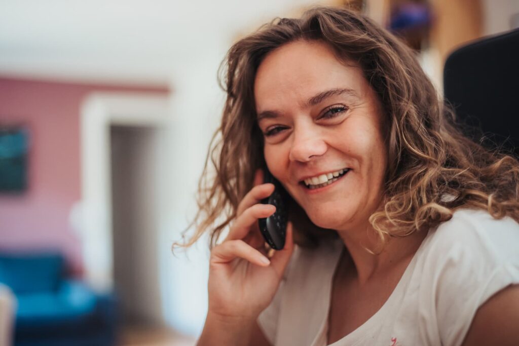 Claudia am Telefon freundlich lachend