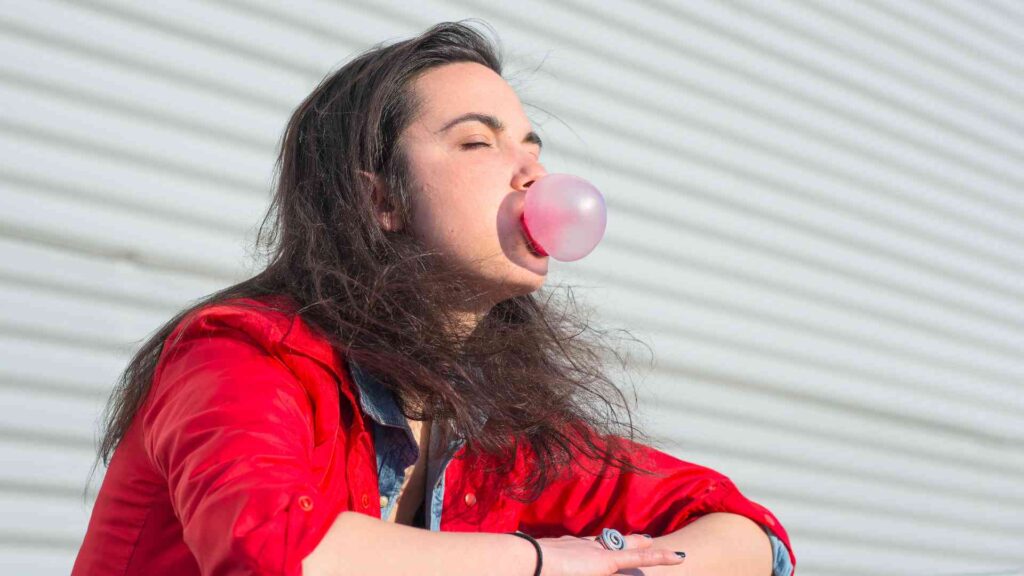Endlich mit dem Rauchen aufhören? Deshalb hat es bisher nicht geklappt - und so änderst du das 2 Junge Frau macht eine Kaugummiblase – orale Gewohnheiten wie ständiges Kaugummi-Kauen können auf restaktive frühkindliche Reflexe hindeuten